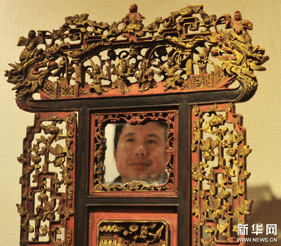 （2）2月9日，一位市民在觀看一個(gè)工藝繁復(fù)的帶鏡木雕盆架。