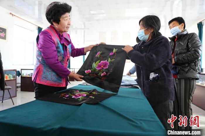 圖為白晶瑩驗(yàn)收繡工的作品?！】朴抑衅煨麄鞑抗﹫D