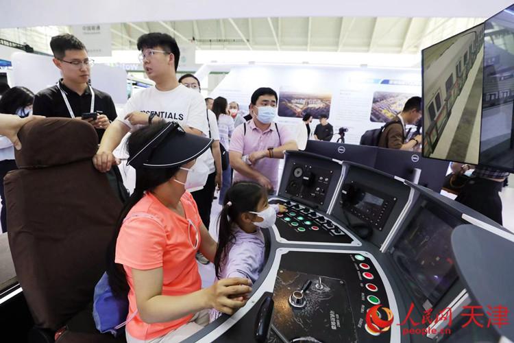 一位參觀者和孩子在天津軌道交通集團展臺體驗智能駕駛帶來的樂趣。人民網(wǎng)記者 孫翼飛攝